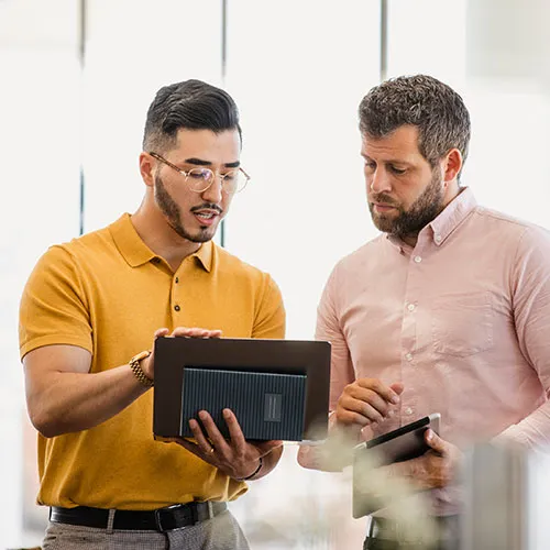 two men looking at an ipad and talking